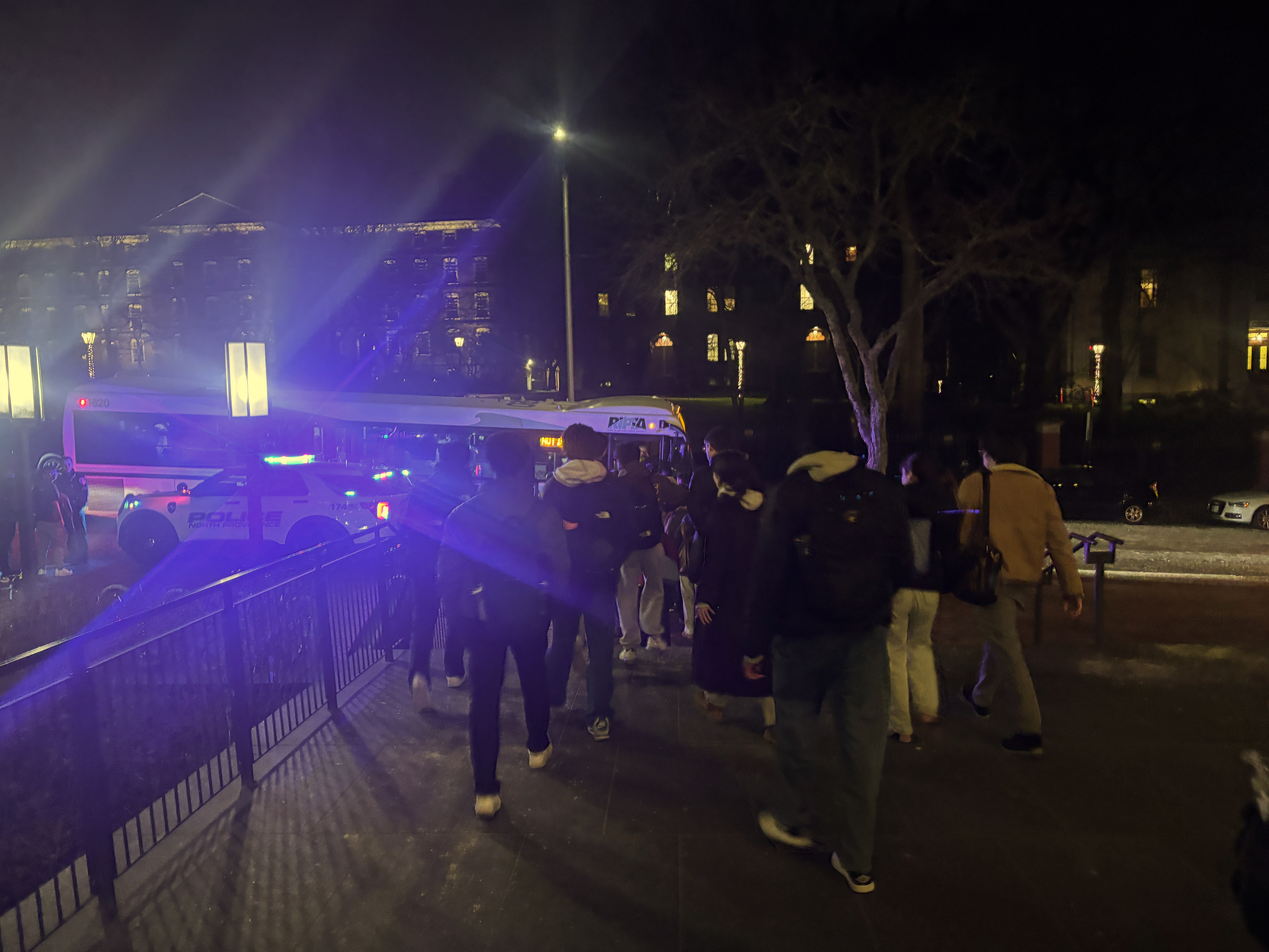 Photo of several students walking towards RIPTA bus parked outside the Quiet Green.