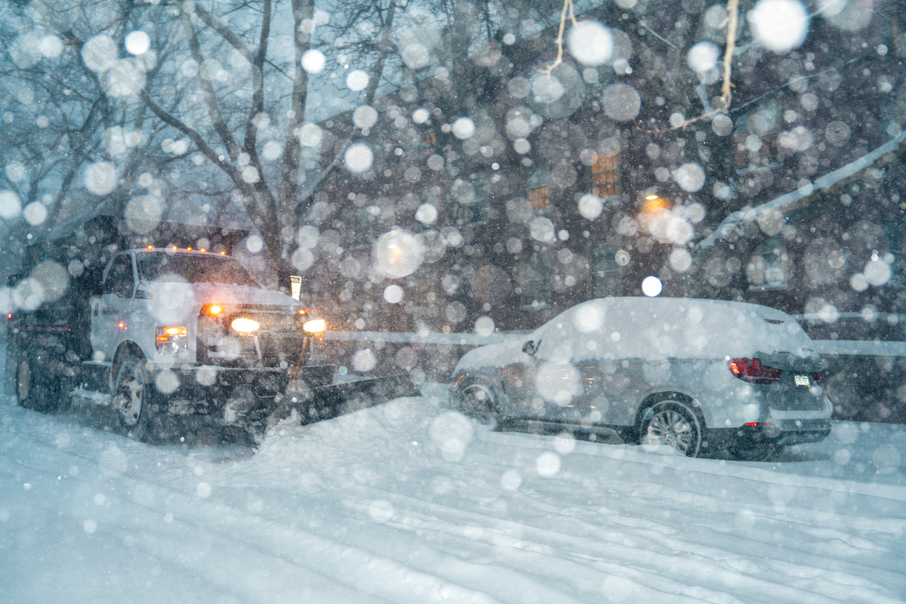 Photo of snow truck plowing through a snow-covered road.