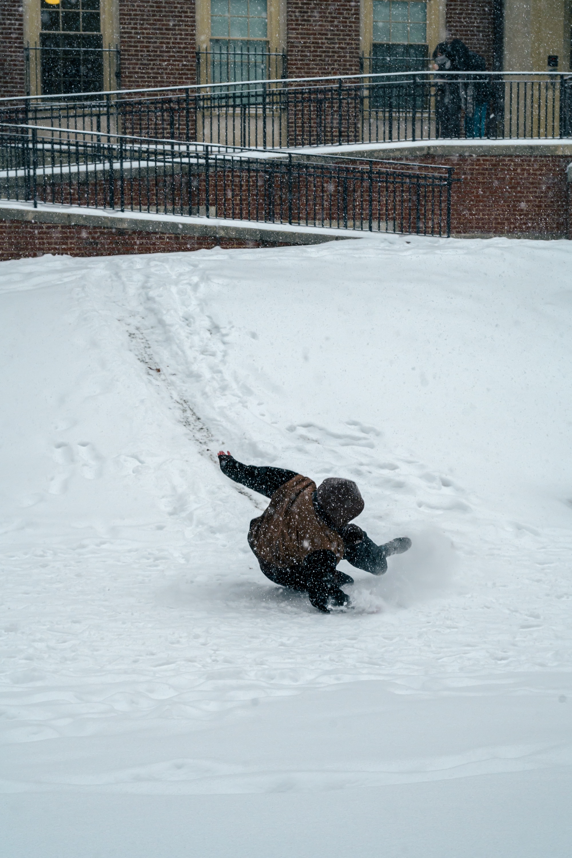 Photo of a student sliding down a hill, leaving a trail of their path.