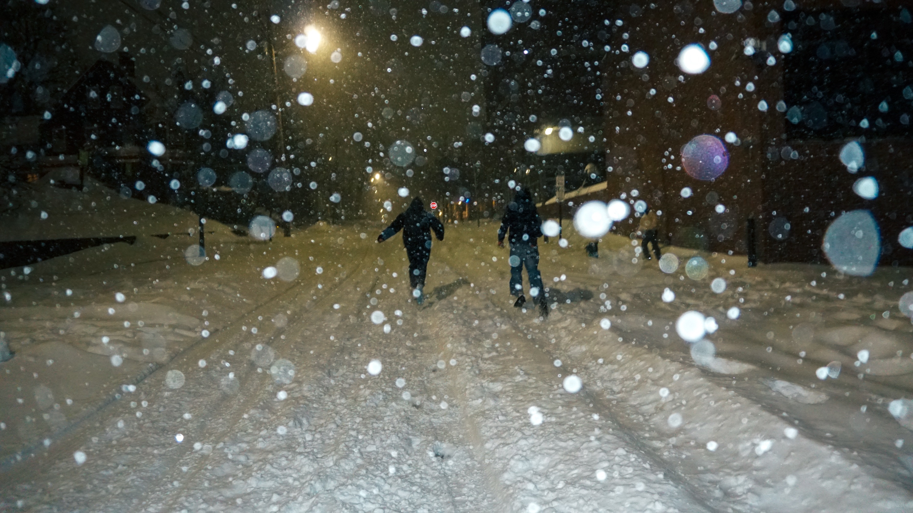 Photo of two students running on the tire marks of a snow-covered road.