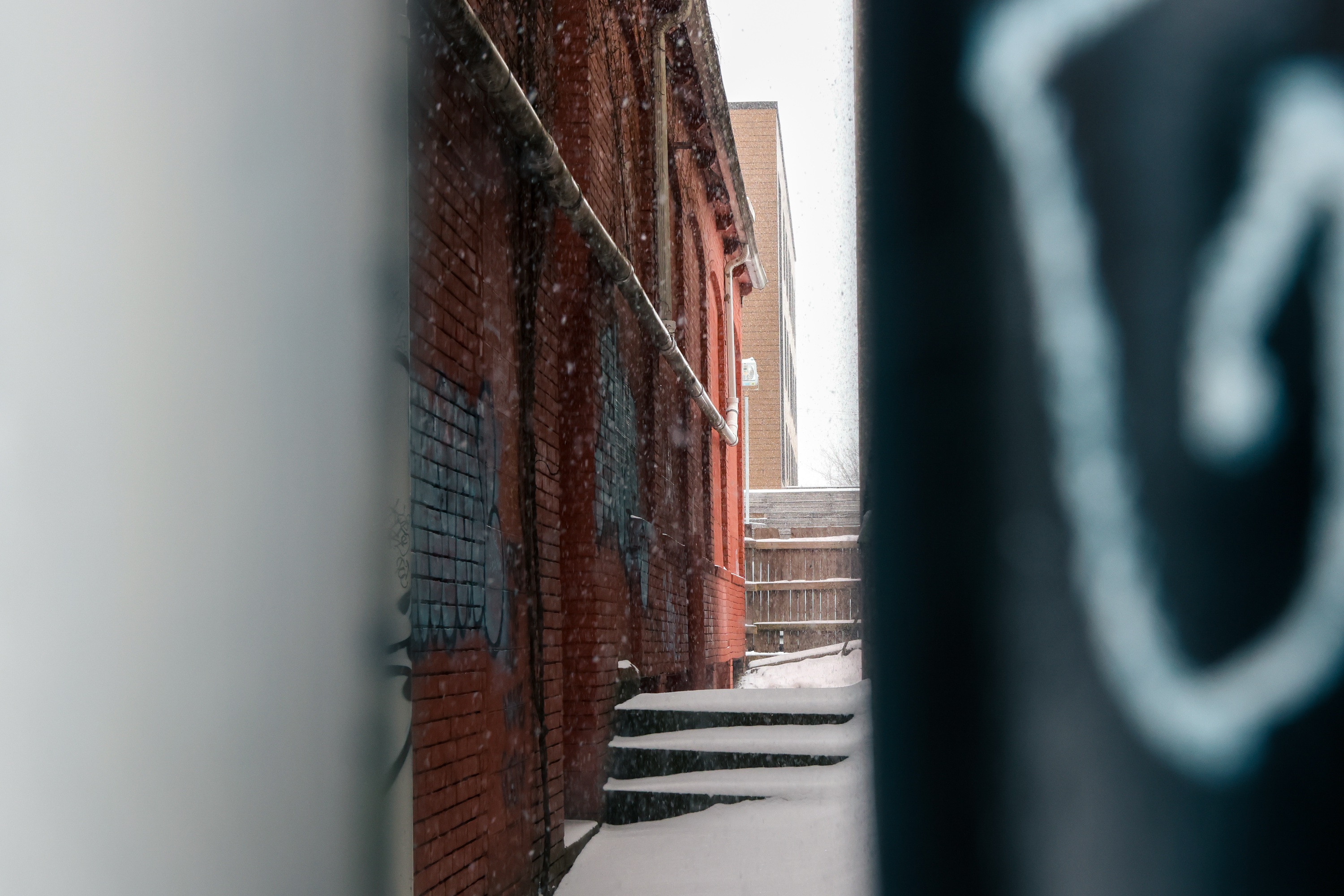 Photo of an alleyway with a short stairecase, slightly obscured by the two walls.