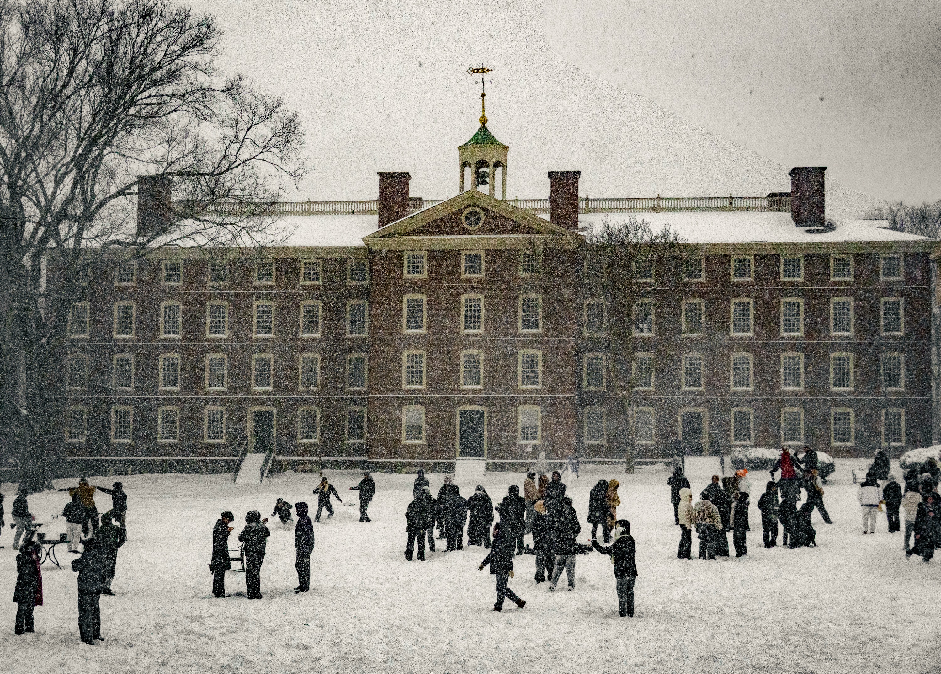 Photo of students, bundled in winter attire, congregating on the Main Green in groups of three to ten.