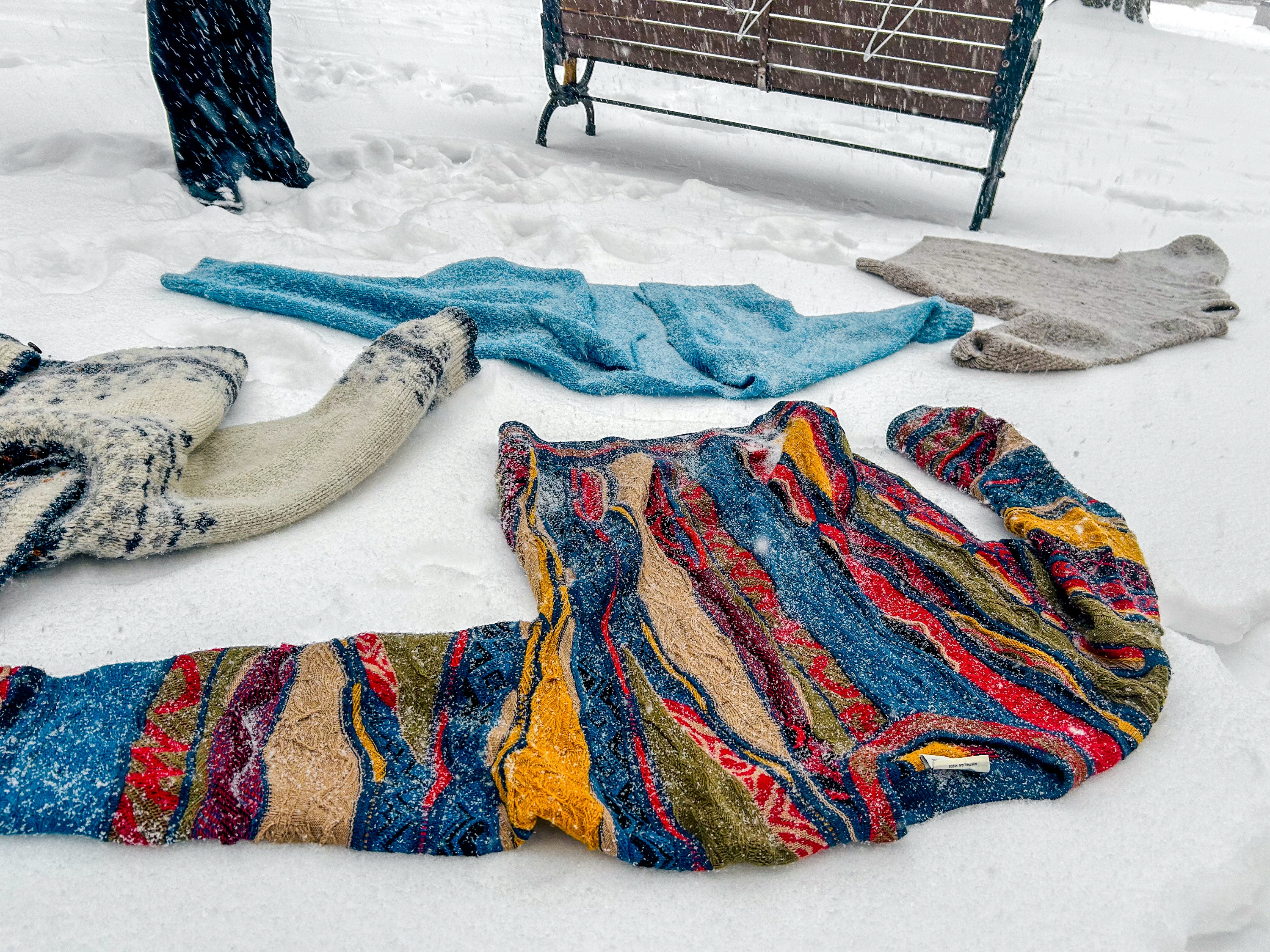 Photo of four wool sweaters lying on the snow.
