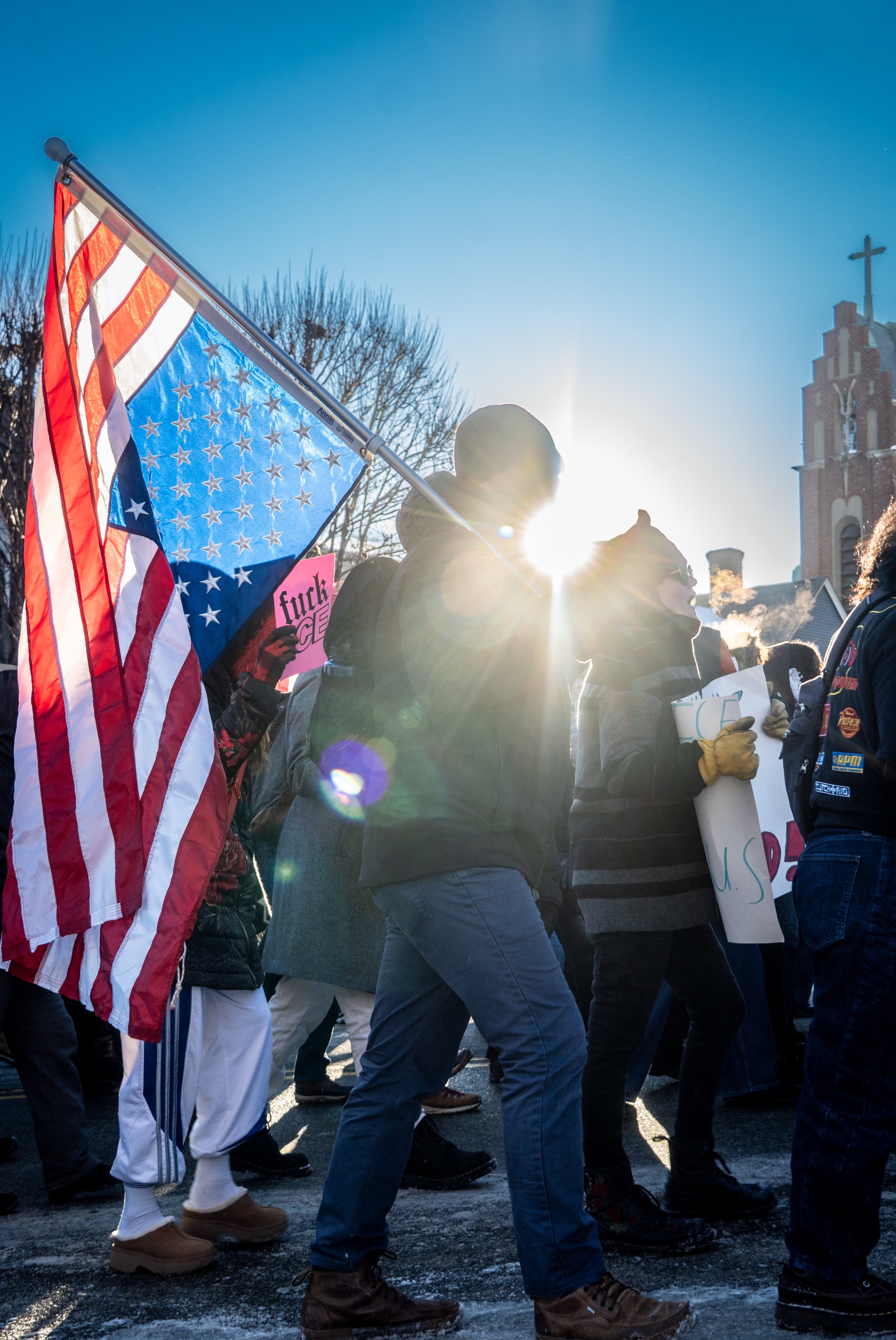 A protester in a crowd carrying an upside-down American flag on a pole.